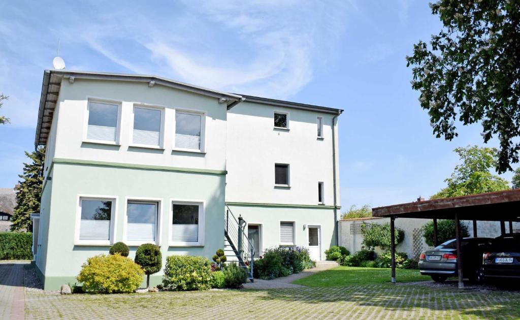 a white house with a car parked in front of it at Ferienwohnung Anne mit Sonnenterra in Altefähr