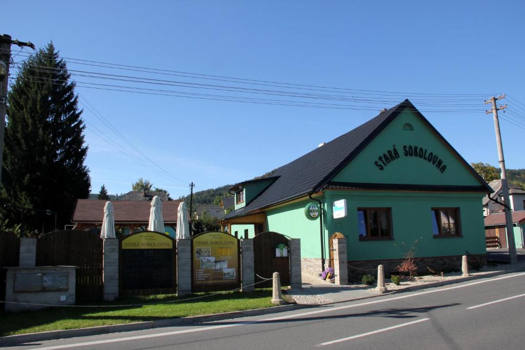 a small green building on the side of a street at Penzion Stará sokolovna in Šumperk