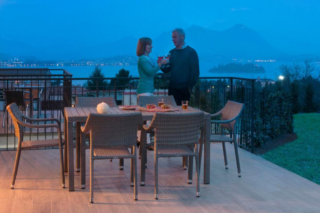 Ein Mann und eine Frau stehen auf einem Balkon mit einem Tisch und Stühlen in der Unterkunft Agrifoglio in Baveno