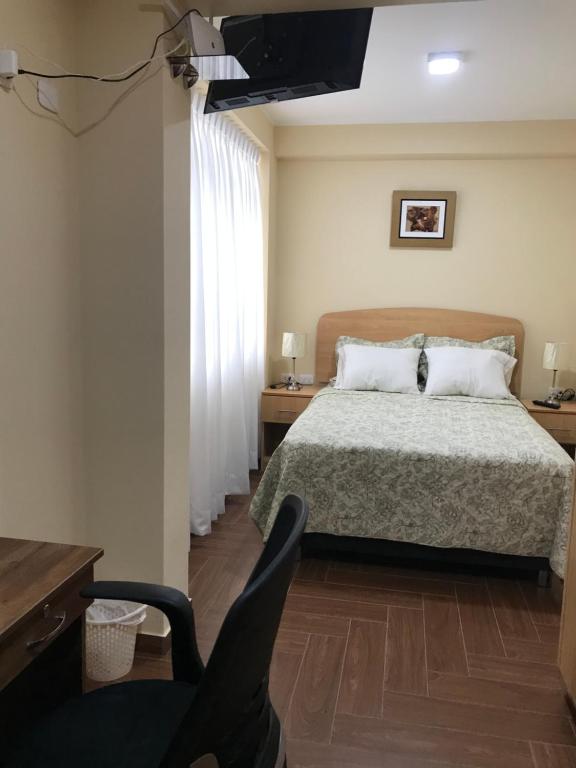 a bedroom with a bed and a desk and a television at Apartamentos Las Americas in Lima