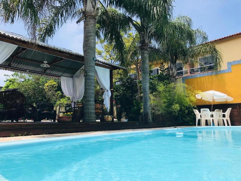 una piscina frente a una casa con palmeras en Pousada Magia do Sol, en Florianópolis