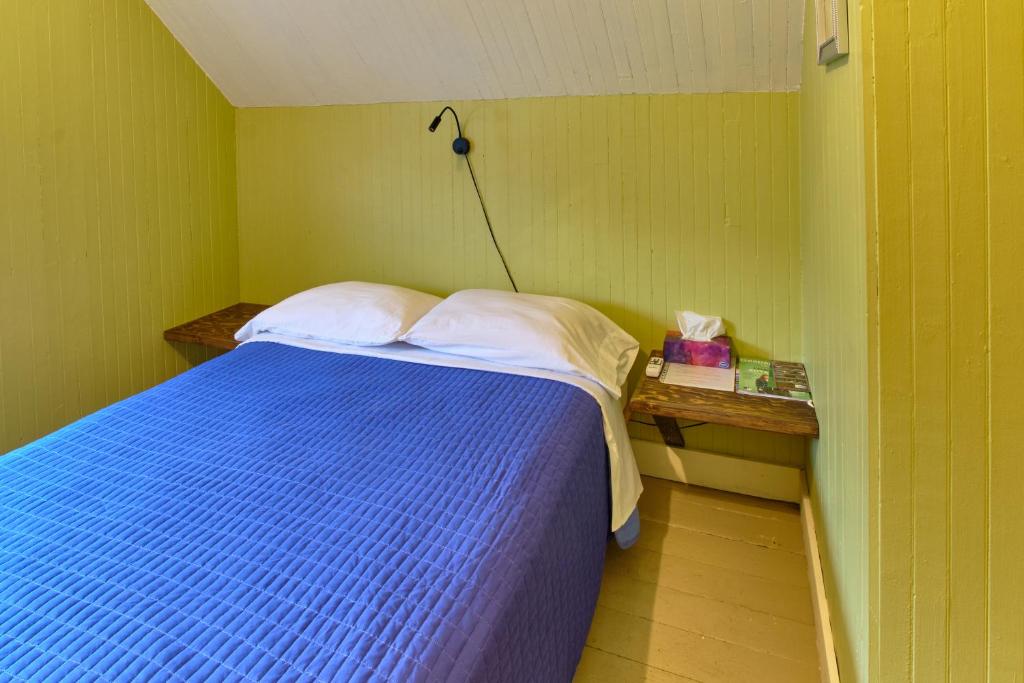Un pequeño dormitorio con una cama azul y una lámpara en Chez Casimir en Matapedia
