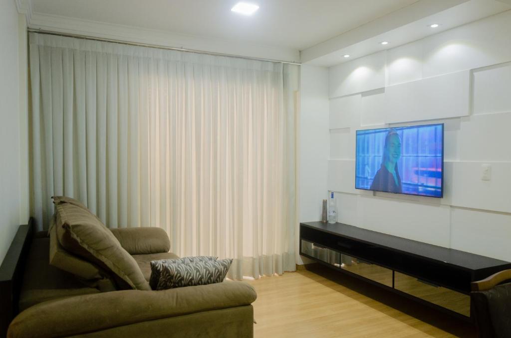 a living room with a couch and a flat screen tv at No CENTRO de Cascavel, atras do Ibis, confortavel e bom gosto in Cascavel