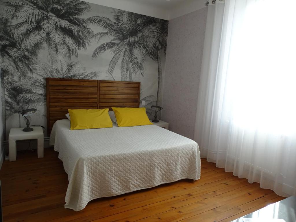 a bedroom with a bed with two yellow pillows at A la Vill'Adour in Dax