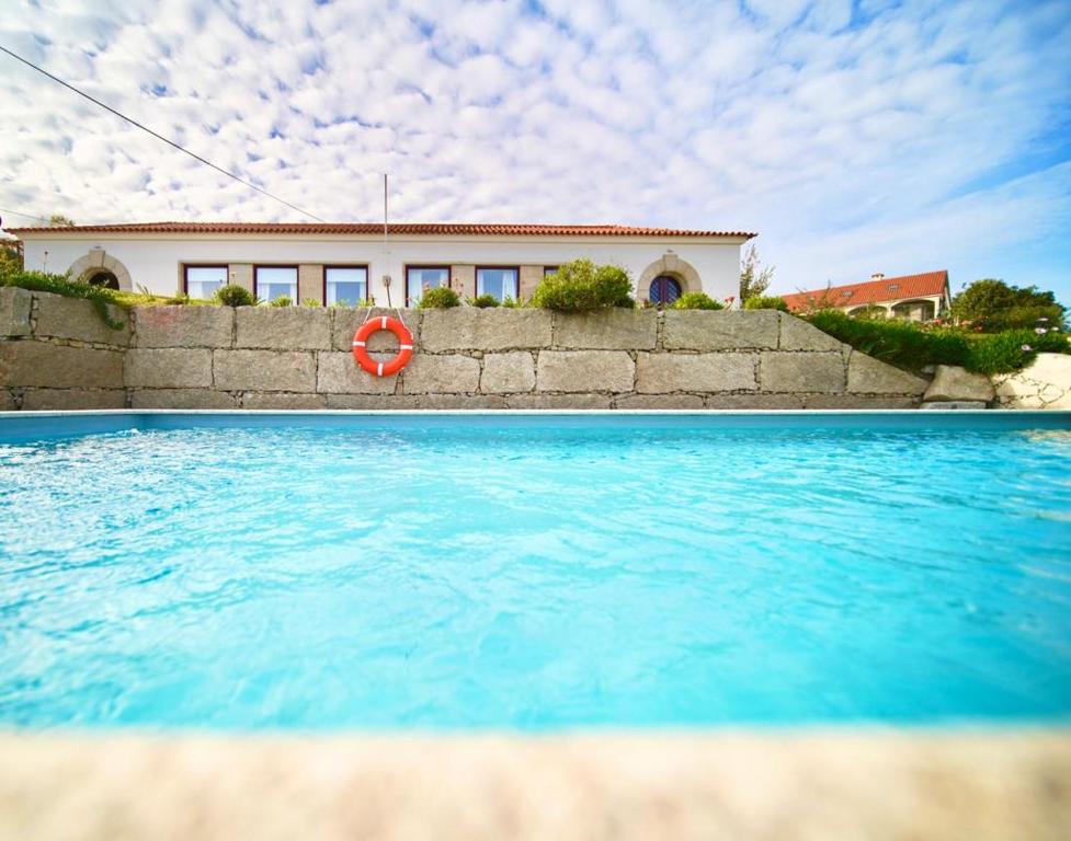 uma piscina com um salva-vidas em frente a uma casa em Burra Velha - Private House em Celorico de Basto