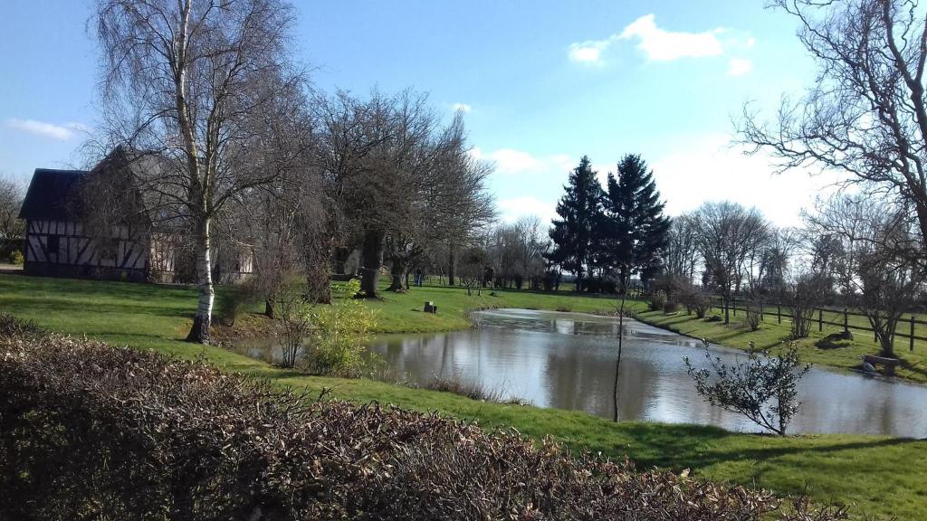 a river in the middle of a park with trees at Le pressoir de gisay in Gisay