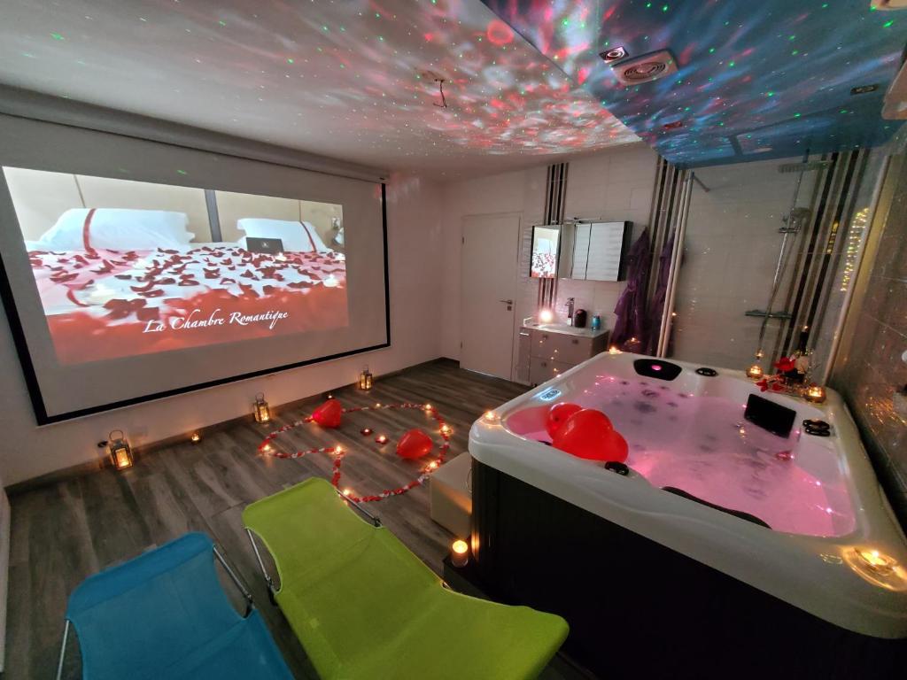 Cette chambre comprend une baignoire avec des chaises et un écran de projection. dans l'établissement LE LOVELYHOME au Centre ville avec SPA JACUZZI et SAUNA proche gare et parking gratuit, à Colmar