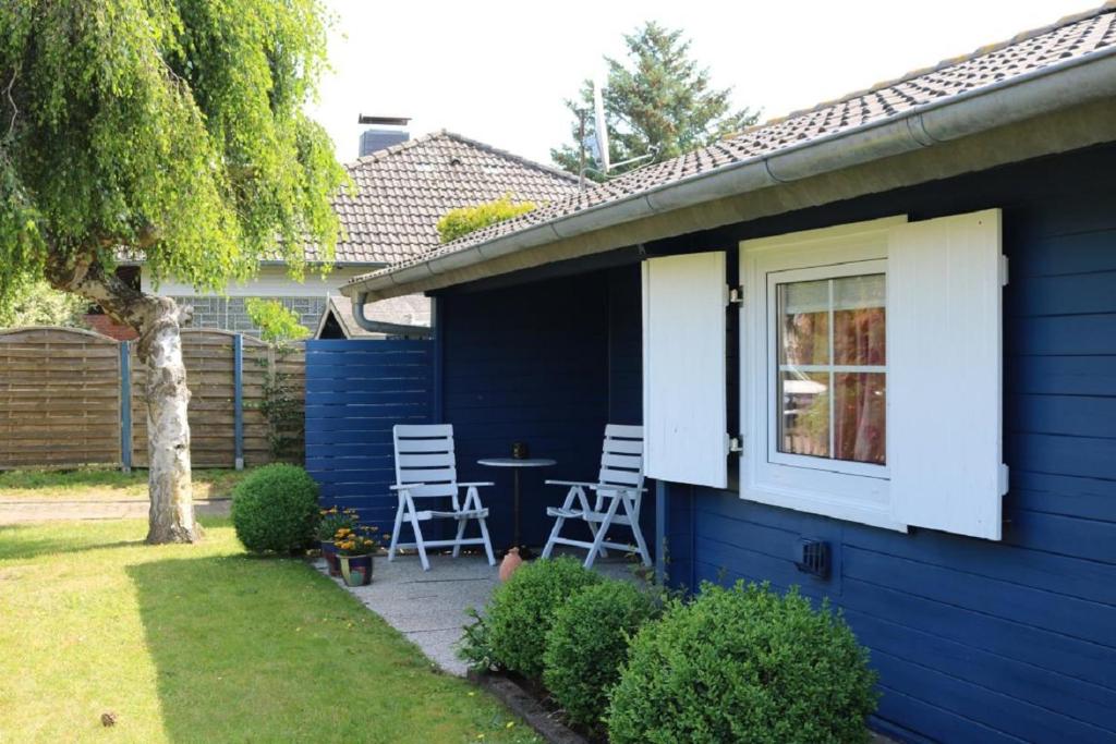 ein blaues Haus mit 2 Stühlen und einem Tisch in der Unterkunft Satelsrönne 02 in Duhnen