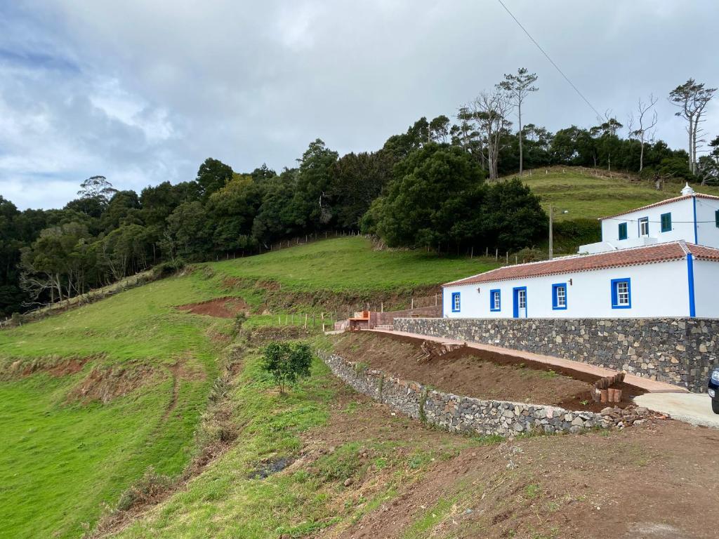 a house on a hill next to a stone wall at Casa da Bisa - Santa Maria - Açores in Santa Bárbara