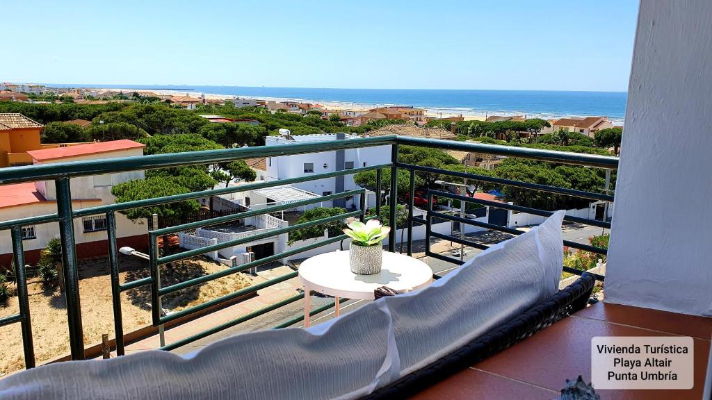 balcón con mesa, sillas y vistas al océano en VIVIENDA TURISTICA PLAYA ALTAIR PUNTA UMBRIA, en Punta Umbría