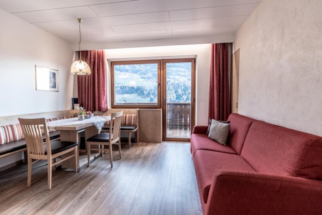 - un salon avec un canapé rouge et une table dans l'établissement Ferienwohnungen Haus Christine, à Rifiano