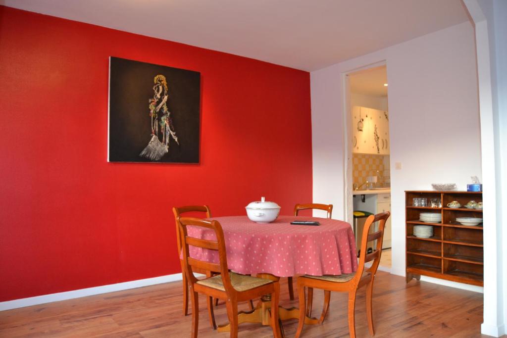 a dining room with a red wall and a table with chairs at L'enfant de Bohème d'Albi, Mon-Appart Hotel-ALBI in Albi