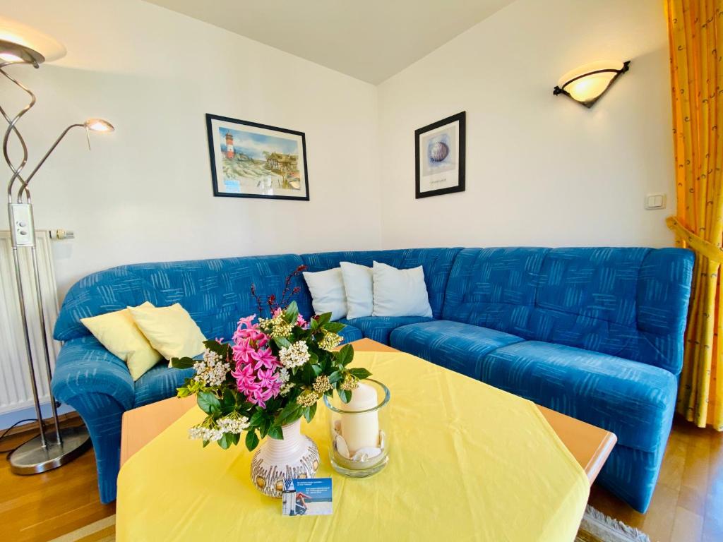 ein Wohnzimmer mit einem blauen Sofa und einem Tisch mit Blumen in der Unterkunft Residenz Bleichröder - Ferienwohnung 27 in Heringsdorf