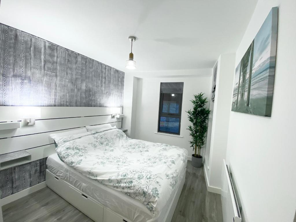 a white bedroom with a bed and a wall at The Works - Private one bedroom apartment in Manchester