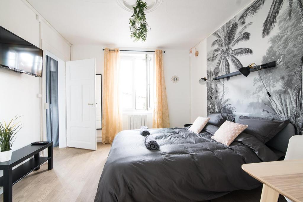um quarto com uma cama preta e um mural de palma em Auguste, La Romaine et My César - Location Saverne em Saverne