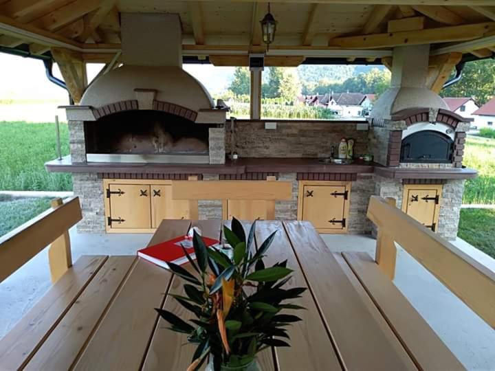 an outdoor kitchen with a wooden table and a stove at Drinska Idila apartmani in Vrhpolje