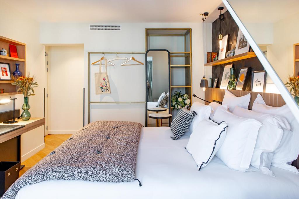 um quarto com uma grande cama branca com almofadas brancas em Maison Mère em Paris