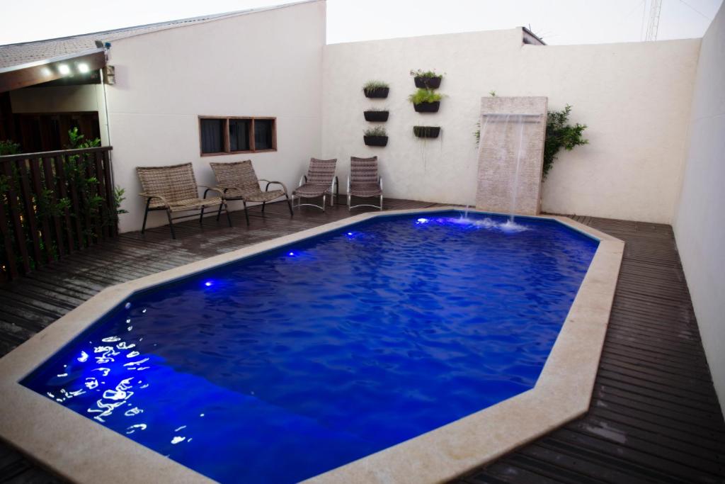 a large blue pool in a patio with chairs at Pousada Remanso in Bonito