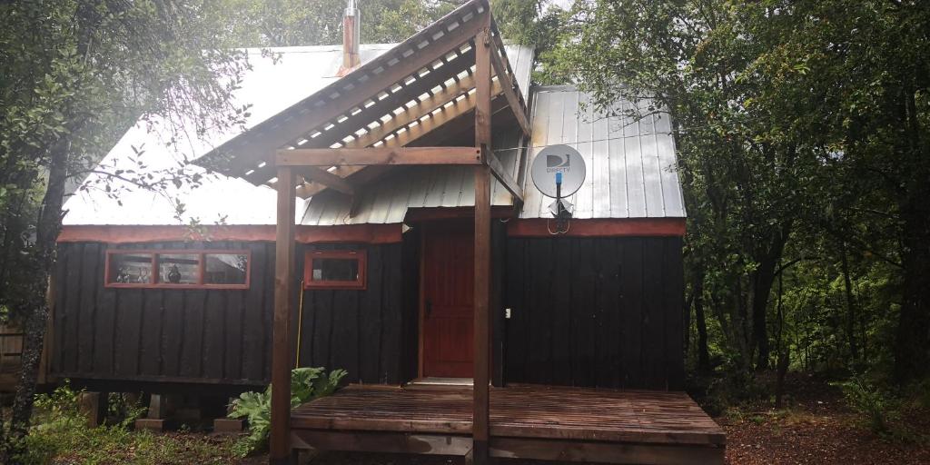Casa pequeña con porche de madera y techo en Lodge Palguin Alto, en Palguín