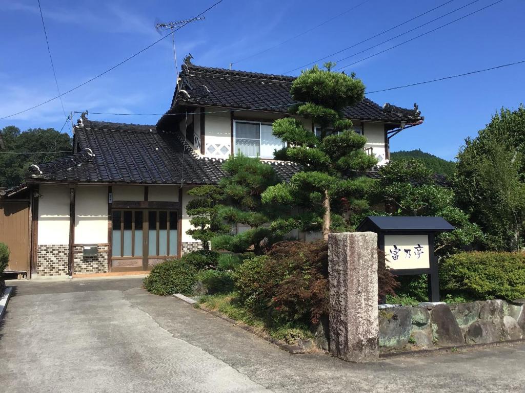 a house with a pine tree in front of it at 富乃亭 in Maniwa