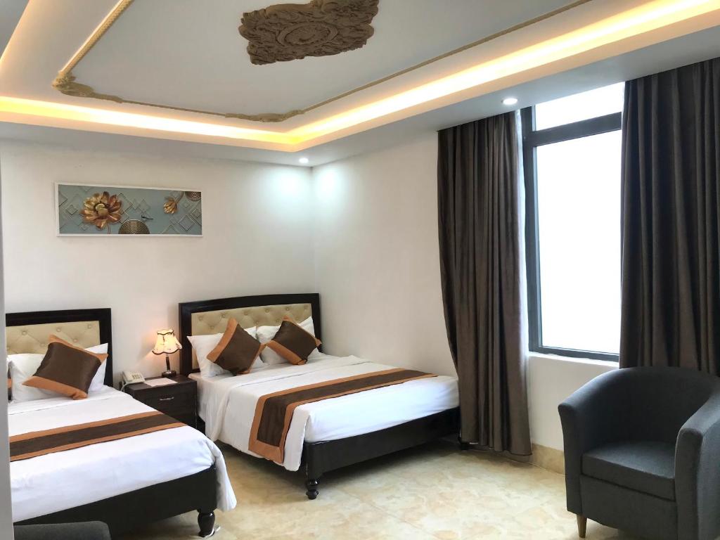 una habitación de hotel con 2 camas y una silla en THẢO AN HOTEL Huế, en Hue