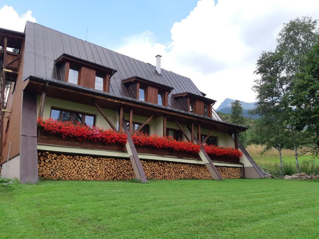 a building with red flowers on the side of it at Tri studničky in Štrbské Pleso