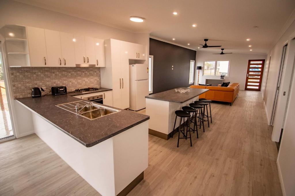 a kitchen with white cabinets and a counter top at Monaro House - Hervey Bay in River Heads