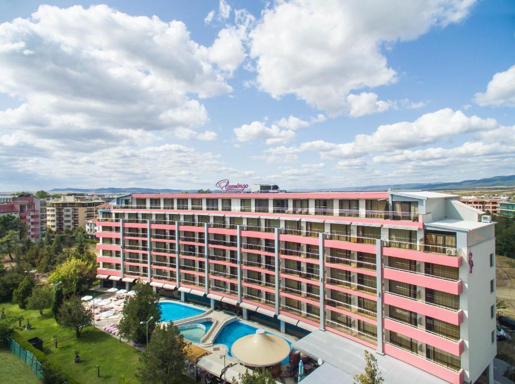 un grand bâtiment rose avec une piscine en face dans l'établissement Flamingo Hotel Sunny Beach, à Sunny Beach