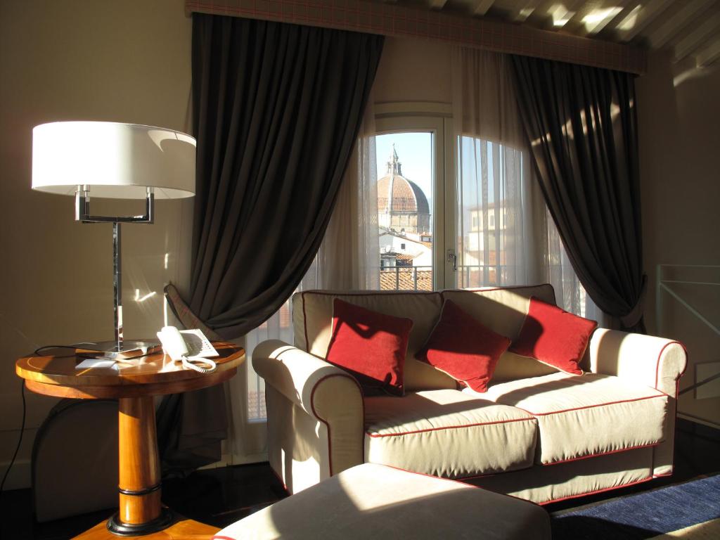 sala de estar con sofá, mesa y ventana en Hotel Patria, en Pistoia