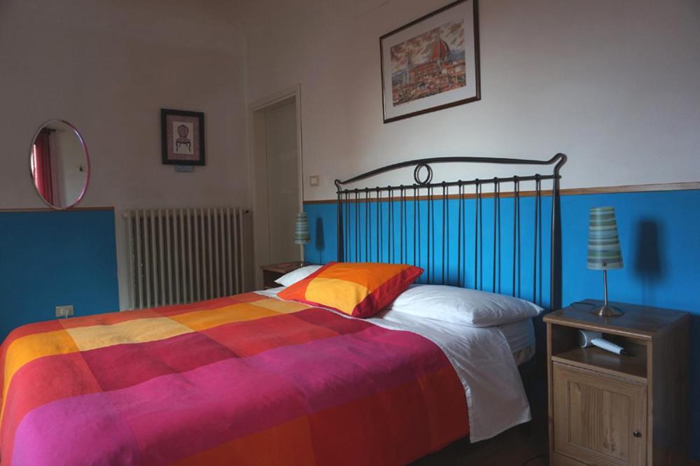 sypialnia z łóżkiem z kolorowym kocem w obiekcie Soggiorno Venere we Florencji
