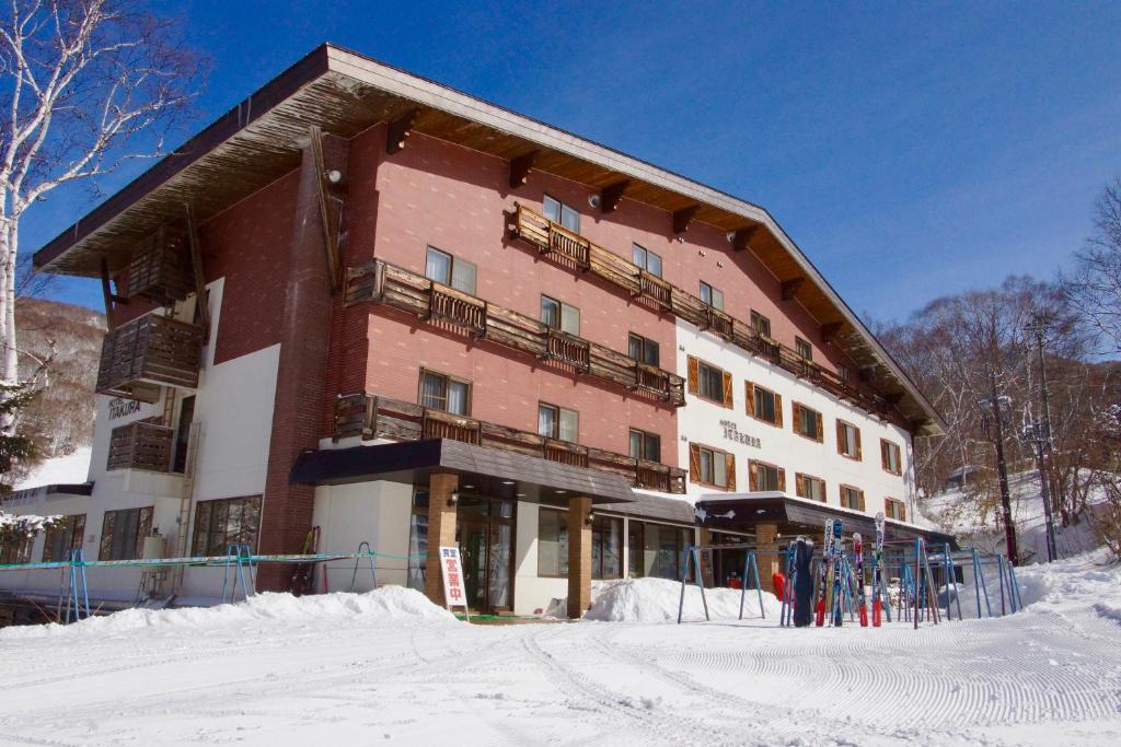 a large building with people standing outside of it in the snow at Onsen Hotel Itakura in Yamanouchi