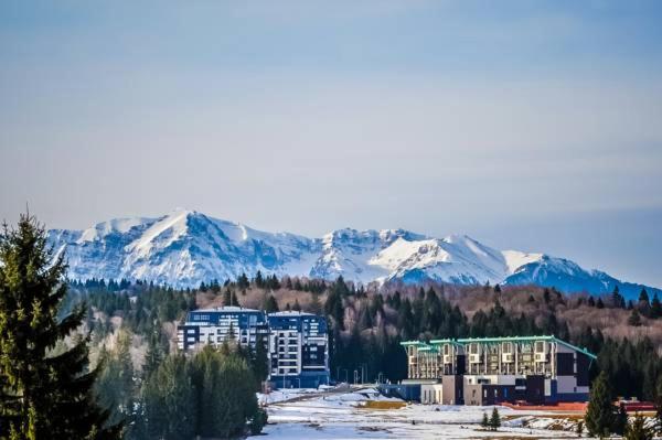a city with buildings and snow capped mountains in the background at Silver Poiana Brasov Ap 41 in Poiana Brasov