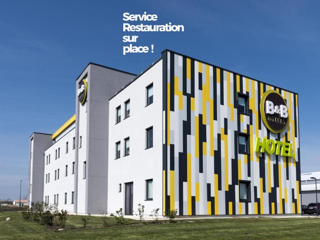 ein großes weißes Gebäude mit einer schwarz-gelben Fassade in der Unterkunft B&B HOTEL Niort Marais Poitevin in Niort