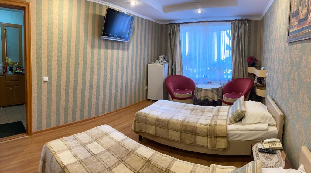 Habitación de hotel con 2 camas y sofá en Hotel Khozyayushka, en Perm
