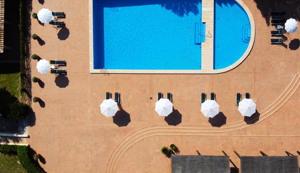a row of white umbrellas on a beach at Son Corb Boutique Hotel in Cala Bona