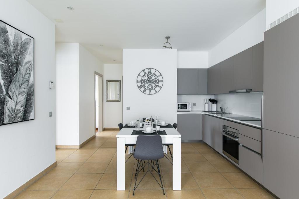 una cucina bianca con tavolo e sedie bianchi di Prestige Apartments by Quokka 360 - spacious flats with terraces a Lugano