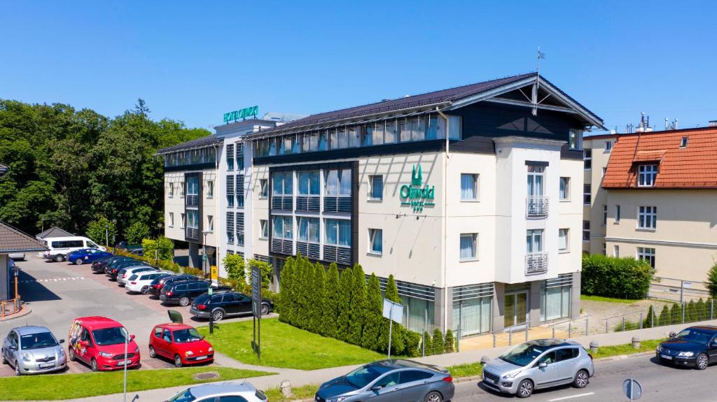 a large white building with cars parked in a parking lot at Hotel Oliwski in Gdańsk