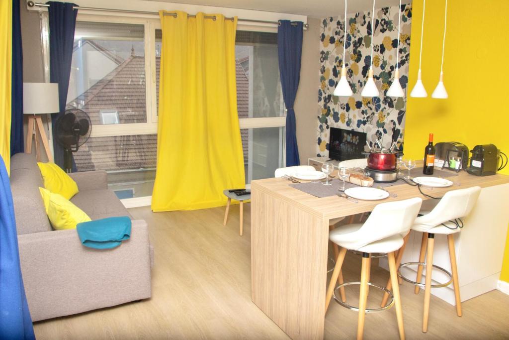 a living room with a kitchen with a table and chairs at APPARTEMENT ENTRE GENÈVE ET CHAMONIX AU PIED DES MONTAGNES in Cluses