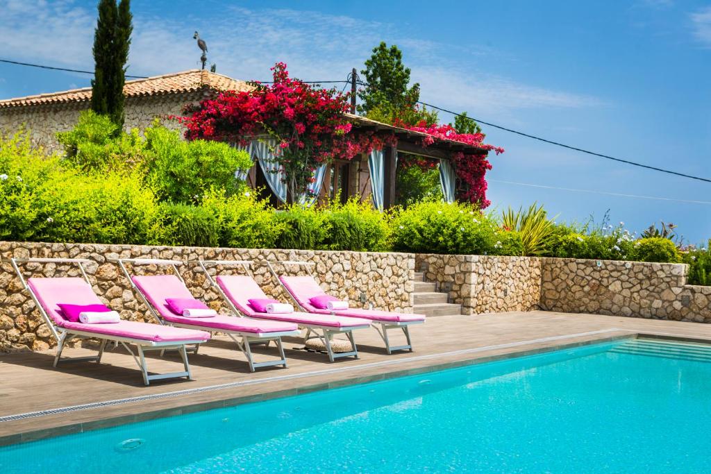 a group of pink lounge chairs next to a swimming pool at Villa Le Rondini in Spartià