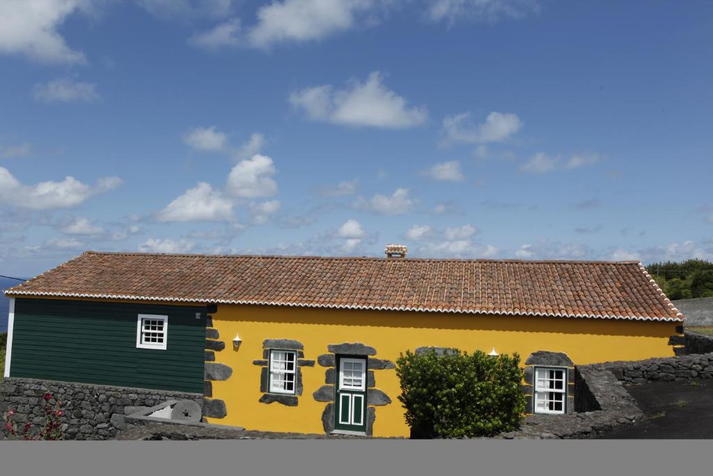 une maison jaune et verte avec un ciel dans l'établissement Casa capelinhos, à Capelo