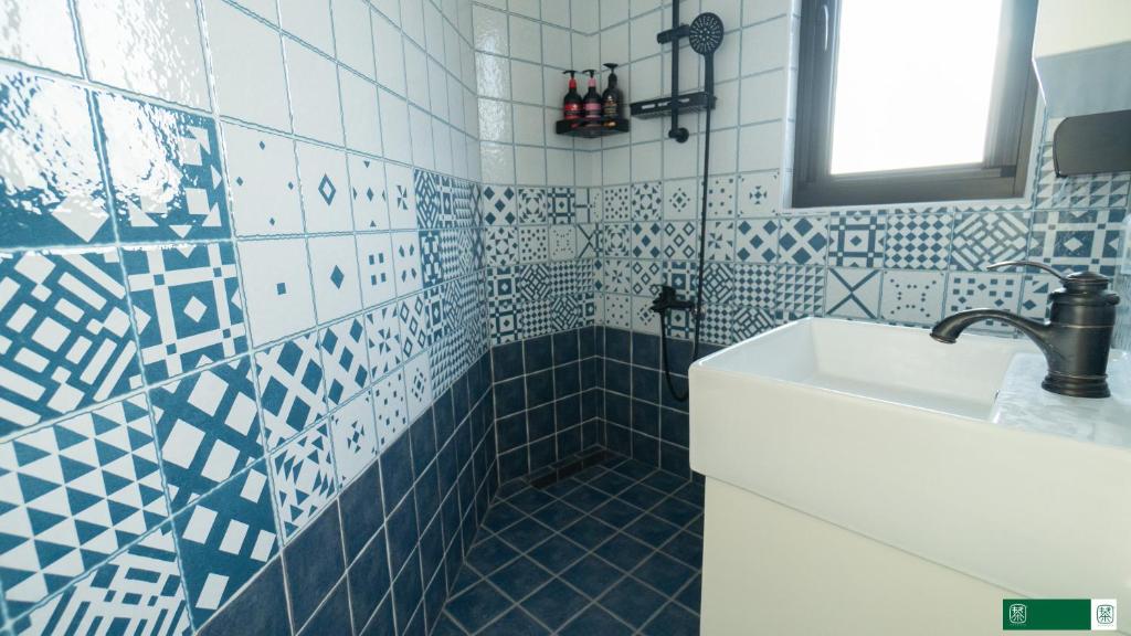 a bathroom with a sink and blue and white tiles at 東莒 找茶複合式民宿-連江縣民宿199號 in Juguang