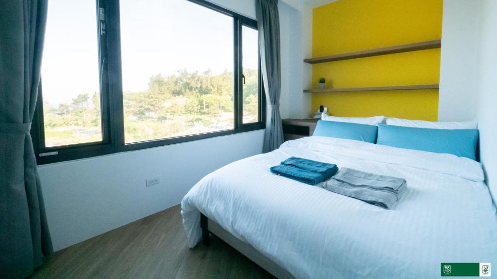 a bedroom with a white bed with blue pillows on it at 東莒 找茶複合式民宿-連江縣民宿199號 in Juguang