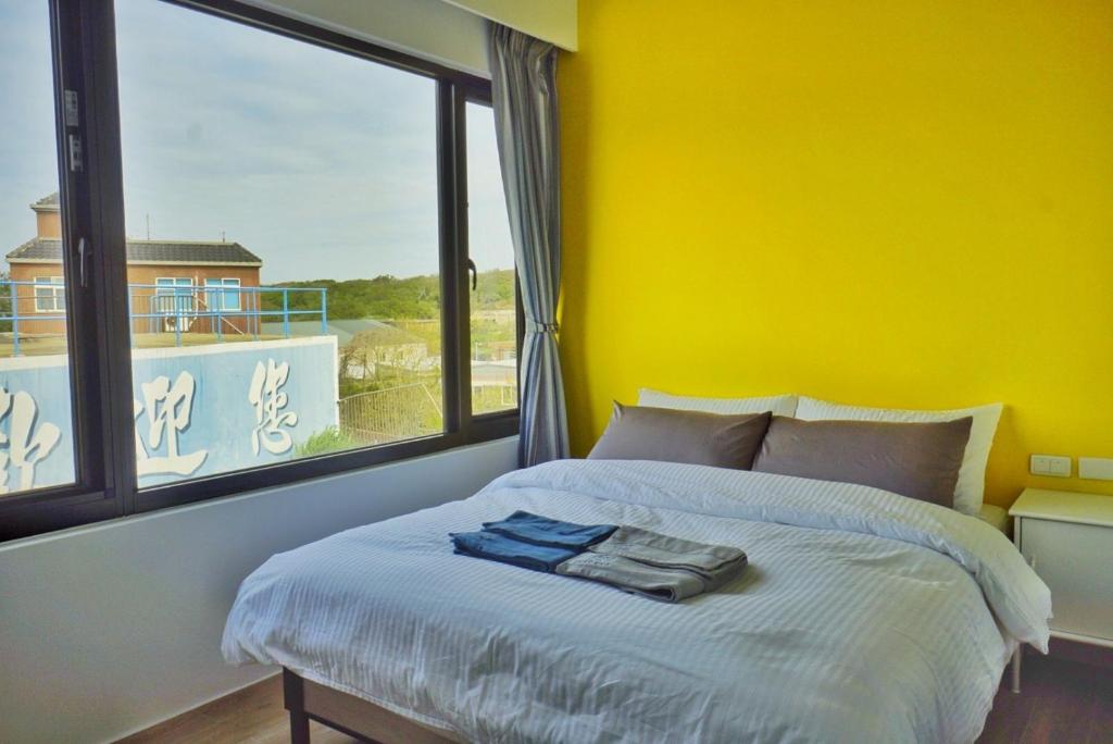 a yellow bedroom with a bed and a large window at 東莒 找茶複合式民宿-連江縣民宿199號 in Juguang