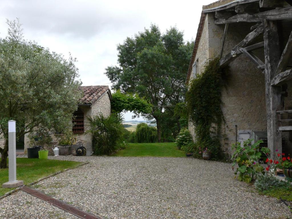 a house with a gravel driveway next to a building at Les Lebes - La petite maison in Sempesserre