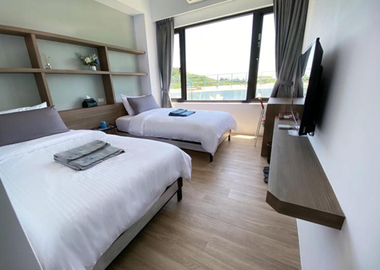 a hotel room with two beds and a flat screen tv at 東莒 找茶複合式民宿-連江縣民宿199號 in Juguang