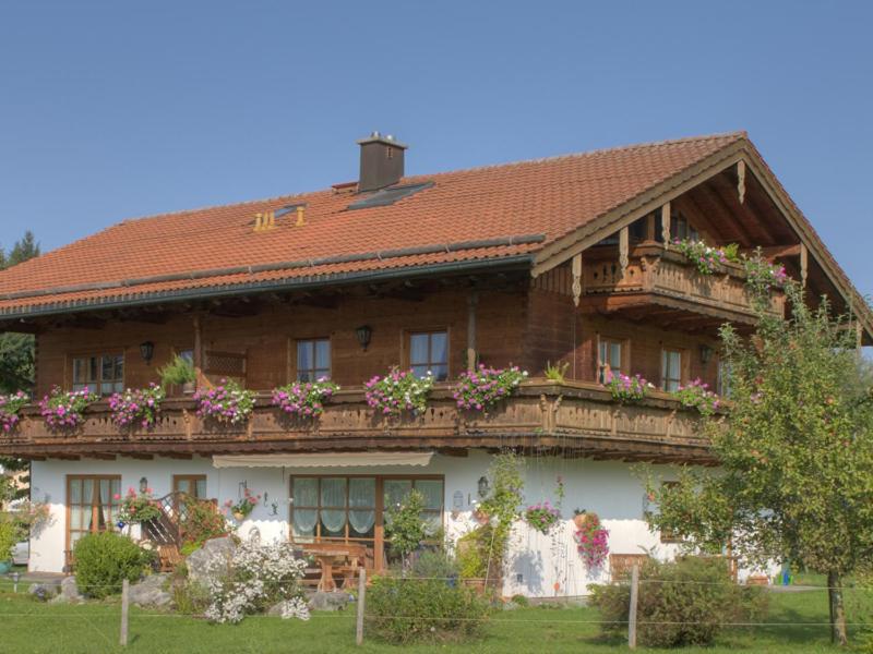 uma grande casa de madeira com flores na varanda em Haus Jung - Chiemgau Karte em Inzell