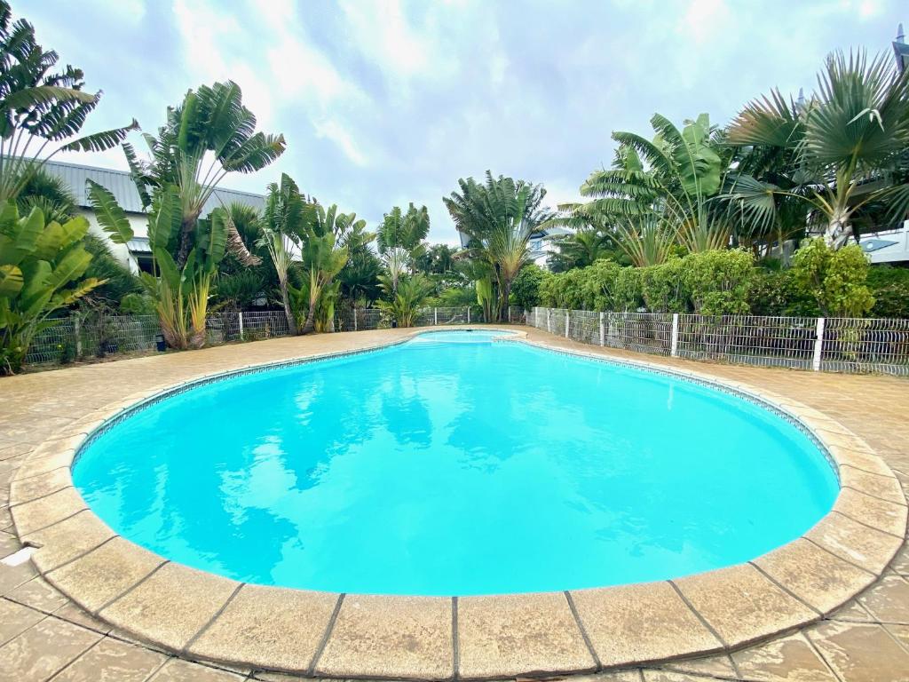 a large pool with blue water in a yard with palm trees at Au bord du Lagon ! in La Saline les Bains