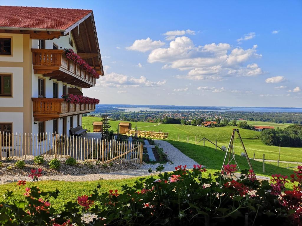 a house with a balcony and flowers on a hill at Schleipfnerhof Urlaub auf dem Bauernhof in Bernau am Chiemsee