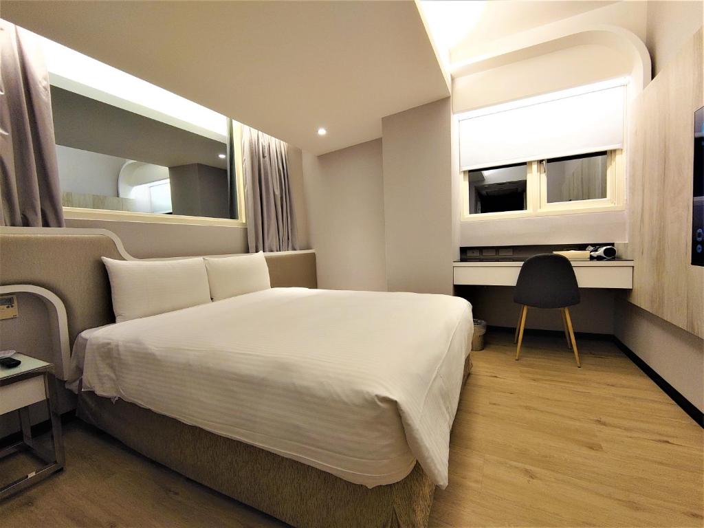 a bedroom with a bed and a desk and a window at Hub Hotel Ximen Inn in Taipei
