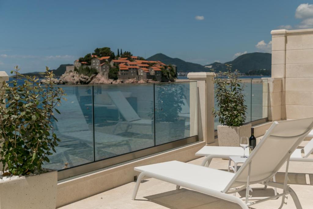 a balcony with a table and chairs and a house at Petra's Beachfront Penthouse in Sveti Stefan